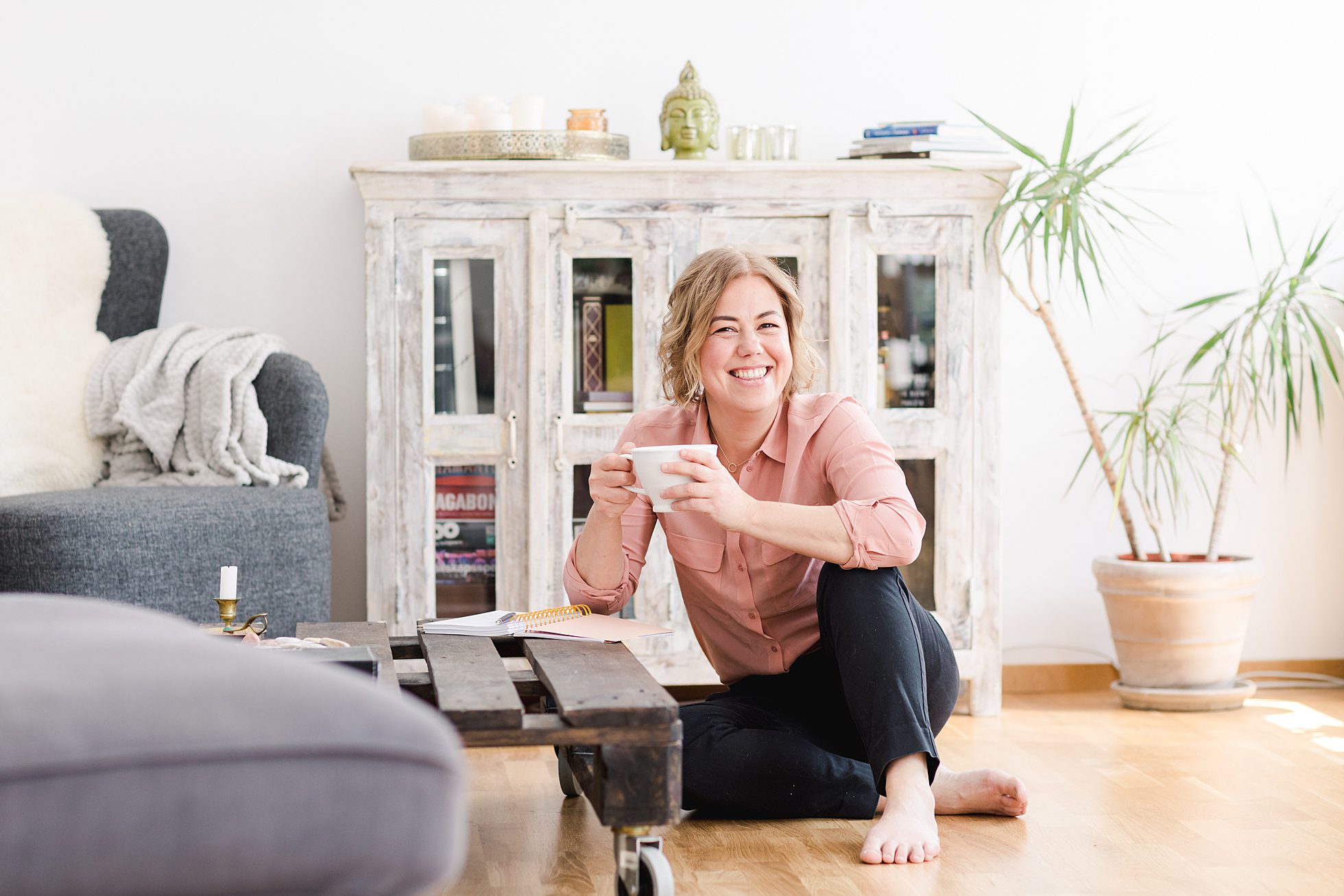 A business woman smiling, holding a cup of coffee