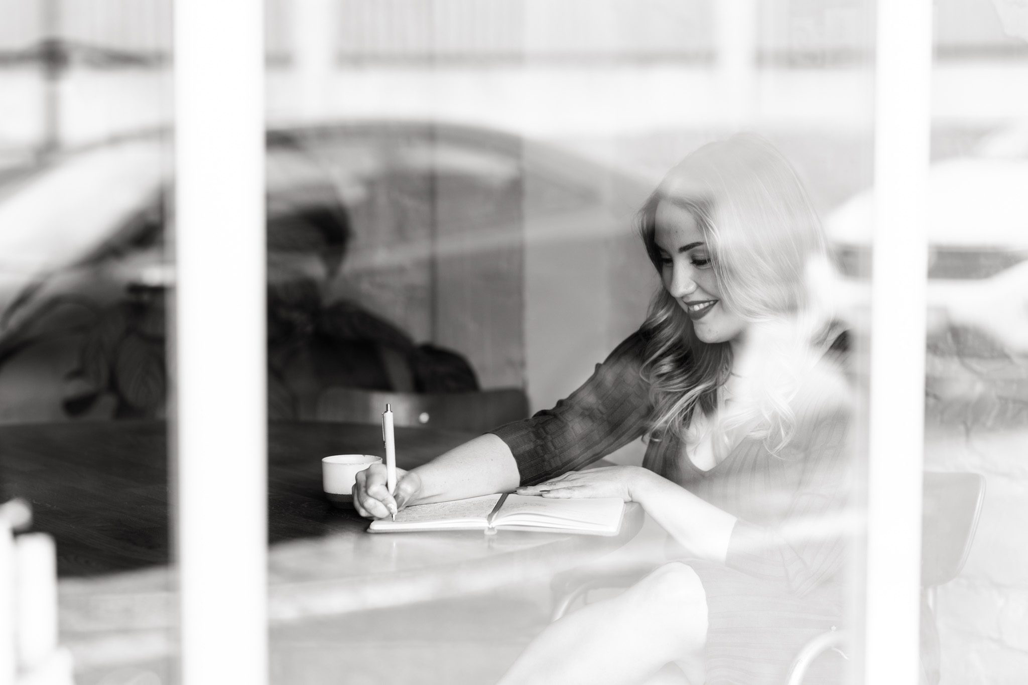 a black and white branding photo of copywriter and coach Megan Taylor as she's writing in a notebook